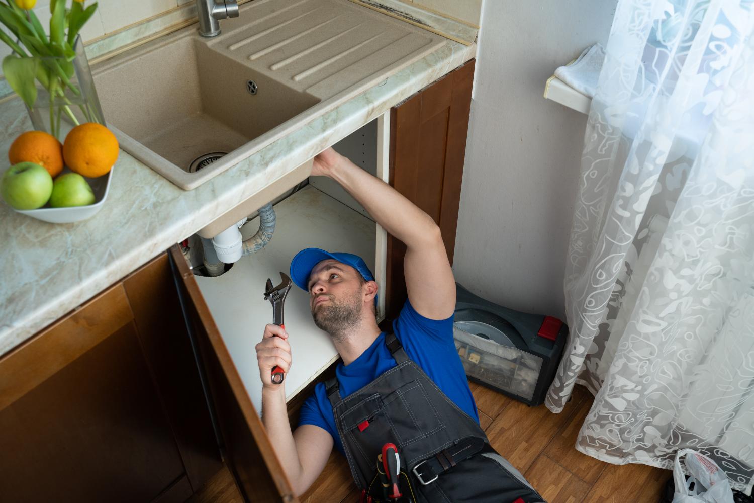 Technician working beneath kitchen sink