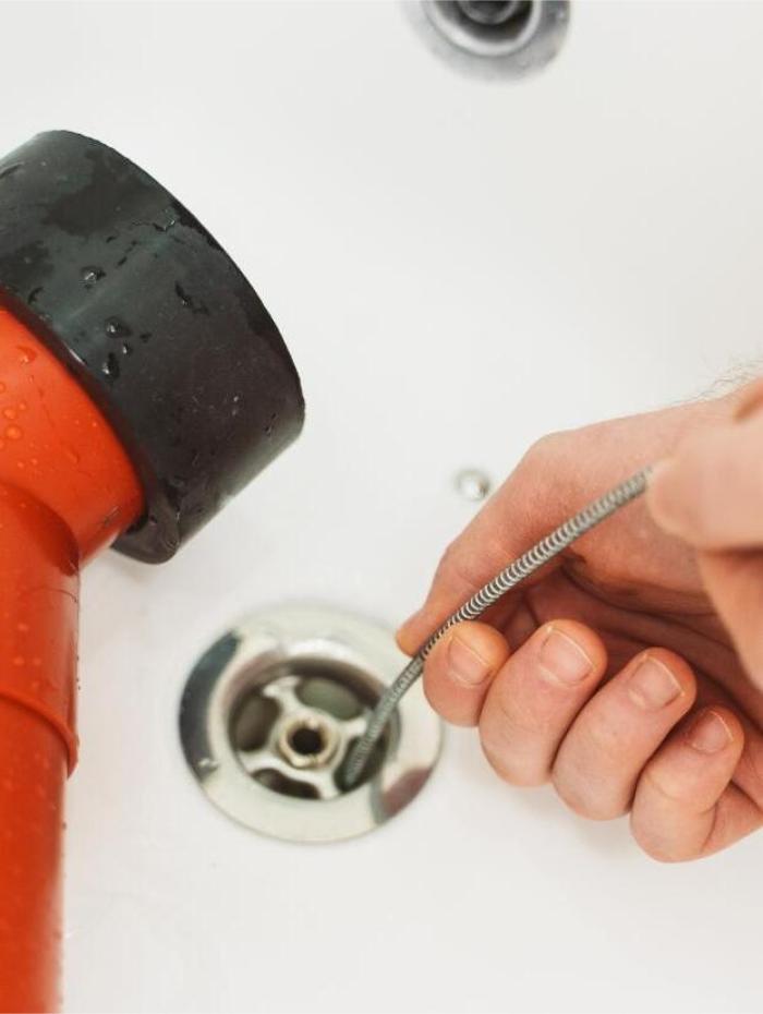 Hand cleaning bathtub drain with snake tool