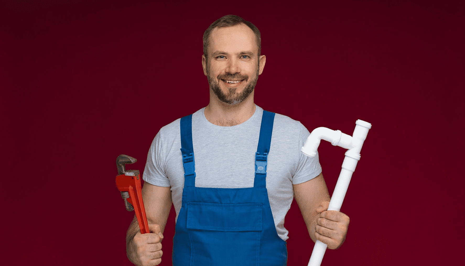 Smiling plumber holding wrench and PVC pipe.