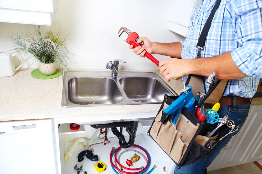Plumber fixing kitchen sink pipes