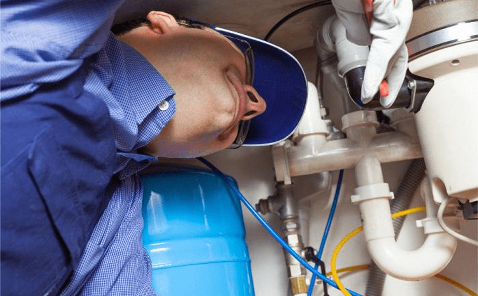 Plumber repairing pipes under the sink.
