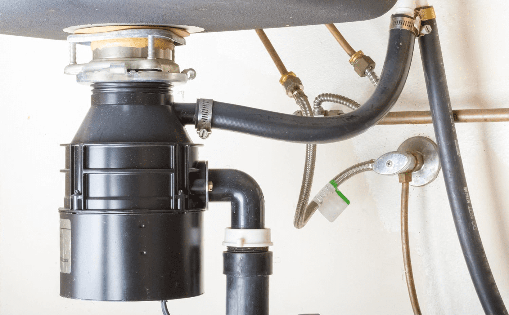 Under-sink garbage disposal unit and pipes.