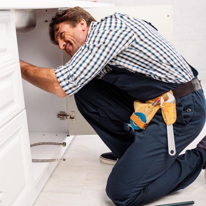 Plumber fixing kitchen sink pipes